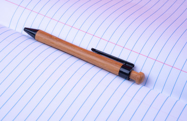 Opened Composition Notebook, Wide Ruled (ruler).  Wooden  Pen between sheets.