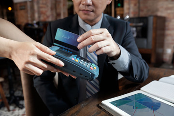Cropped image of entrepreneur paying with credit card for coffee in restaurant