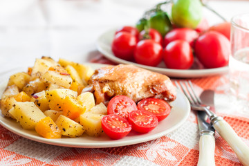 Baked chicken thigh with baked potatoes and pumpkin garnish
