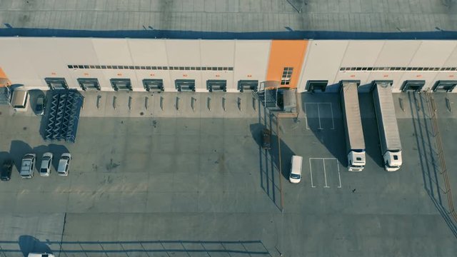 Aerial view of modern warehouse terminal with semi-trailer trucks. Side shot