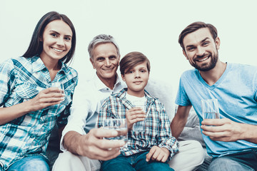 Smiling Family Drinking Water in Glasses at Home.