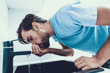 Man in Shirt Drinking Water in Kitchen at Home.