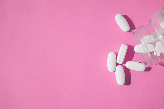Placebo pills, fake medical treatment. Close up white pills with bottle on pink background.