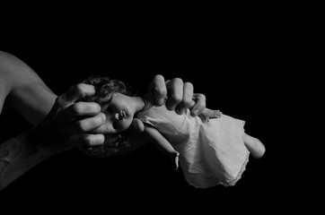 Angry man tearing baby doll.
