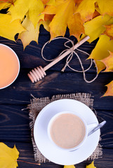 Autumn still life. Fall leaves with dark coffee with milk in a white bowl on a black table