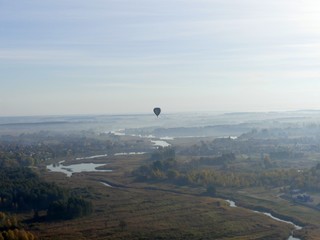 Colorful hot air balloon flying over rock landscape in blue sky