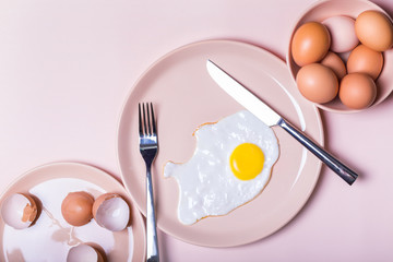 Fototapeta na wymiar Scrambled eggs on a beige plate. Nearby lie on the table fork and knife. simple breakfast