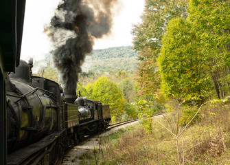 Old steam locomotive running down the tracks with black smoke pouring from its pipe