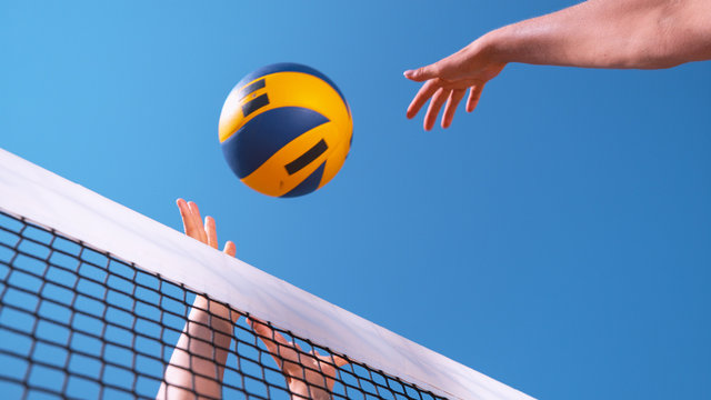 CLOSE UP Female volleyball player's hands score point by spiking ball over hands