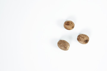 Top view of nutmeg seed on white background, isolated. Whole three seeds of nutmeg isolated. The concept of seasoning dishes, using spices and herbs for meals.