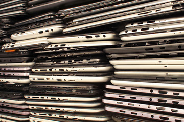 Stacks of disassembled tablets and smartphones. Plastic cases with boards and connectors. Electronics waste concept background.