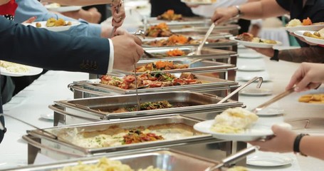 People group catering buffet food indoor in luxury restaurant with meat colorful fruits and vegetables. Close up. Banquet, lunch, bad nutrition, gluttony concept