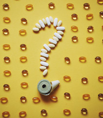  centimeter tape and question mark of pills on a colored background with space for text. concept of losing weight, diet, fat burning, healthy eating.