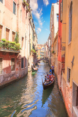 Venice - August 27: Gondolier drives a gondola with tourists on board on the Canal on August 27, 2018 in Venice, Italy