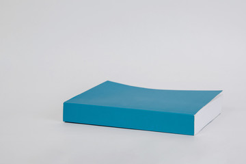 A blue, blank book on a white, bright background. A book with a blank cover ready to complete the content. The concept of reading books, printing a book.