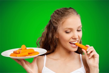 Beautiful young woman eating a carrots