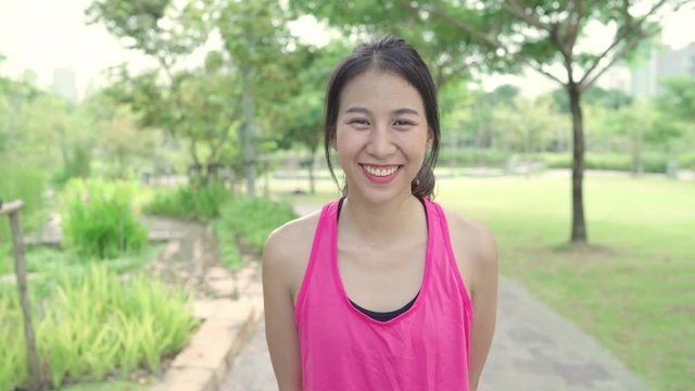 Healthy beautiful young Asian runner woman feeling happy smiling and looking to camera after running on street in urban city park. Lifestyle fit and active women exercise in the city park concept.