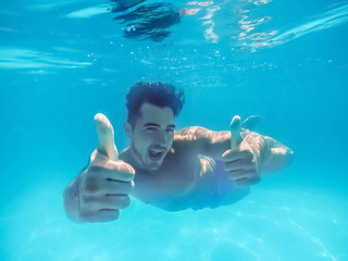 Handsome young man swimming in pool, underwater view