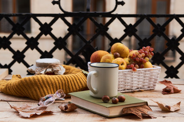 Cup of coffee old book glasses and autumn leaves with fruit basket on rustic wooden table on terrace background. Morning breakfast, seasonal, book reading, Sunday relaxing and still life concept
