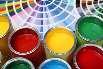 Paint cans and color palette samples on table, closeup