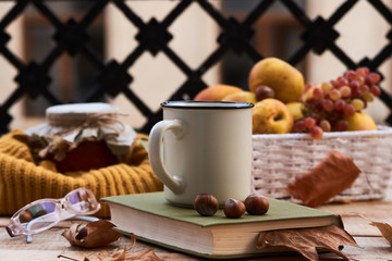 Cup of coffee old book glasses and autumn leaves with fruit basket on rustic wooden table on...