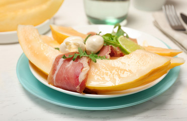 Plate with melon and prosciutto appetizer on light table