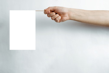 A white, empty flag held in a hand on a bright pastel background. The concept of completing...