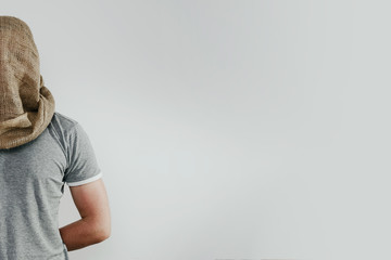 Man with veiled face on a light background. The concept of kidnapping, detention, and crime. No face. The man has a cloth bag on his head. Kidnapping by terrorists.