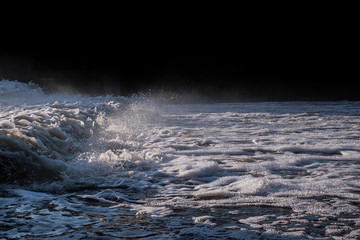 Artificial rapids on the river. Huge waves, splashes, dark water