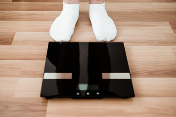 Front view of a man's feet and weight. The man will weigh. The concept of a healthy lifestyle, taking care of your weight. Problems with obesity, overweight and health problems.