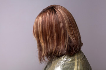 Profile side view of woman with highlighted brown hairs. indoor studio shot, isolated on gray background.