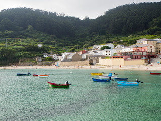 Paisaje de playa con barcas de colores y agua verde y transparente, en Praia da Concha en Lugo, España, verano de 2018
