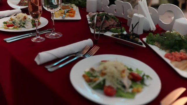 Motion and selective focus of food and drinks on table of party and dinner in luxury restaurant. Pink champagne in glass standing near tasty and fresh classic salad cezar with chicken.