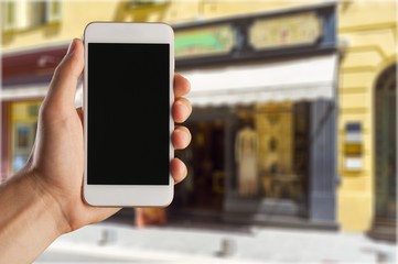 Hand holding smartphone on blurred city background