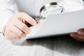 Businessman Analyzing His Documents With A Magnifying Glass