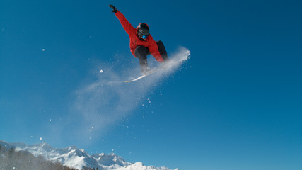 Male snowboarder doing a spectacular grab trick as he flies through the air.