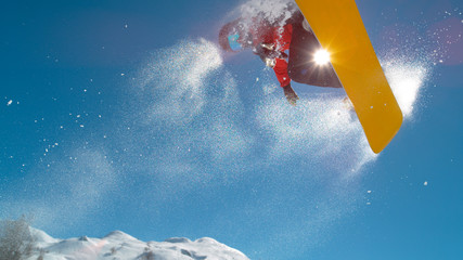 CLOSE UP: Athletic young male snowboarding spins in the air while doing a grab.
