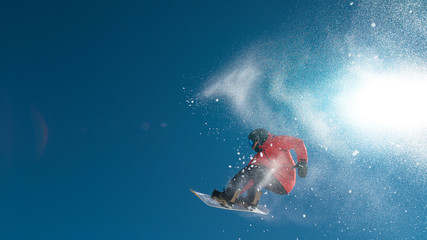 Professional extreme snowboarder spins through the air while holding his board.