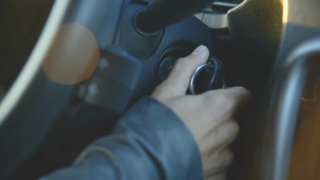 Close-up girl turns the ignition key to start the car. Woman driving a car
