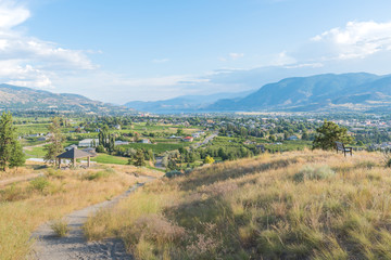 Walking trail on Munson Mountain with view of city of Penticton in distance in summer