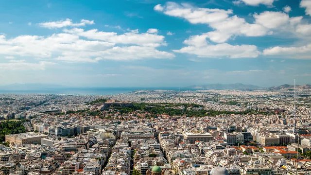 Panoramic view of Athens with ancient Acropolis. White clouds move across the blue sky. Time lapse video.