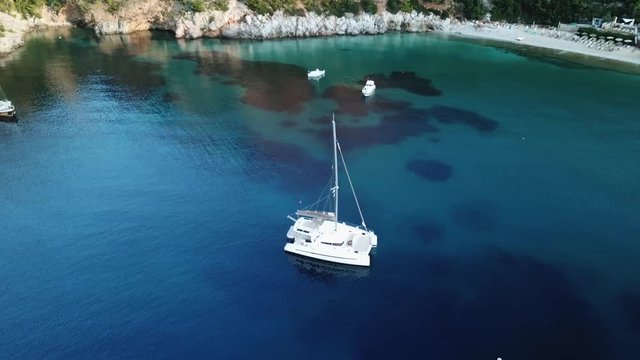 Aerial view of a greek bay with green and bule sea with Sailboats anchored,Early morning sunlight