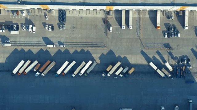 Aerial top view of a warehouse logistic terminal with a lot of commercial vehicle. Side shot