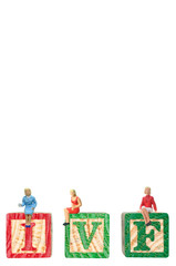 Clipping path included, selective focus miniature girls women sitting on IVF wooden blocks isolated on white background.
