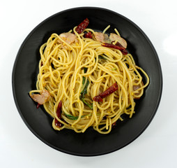 Spaghetti with Dried Chili And Crispy Bacon yellow line in a black dish on white background,Top view,Close up..