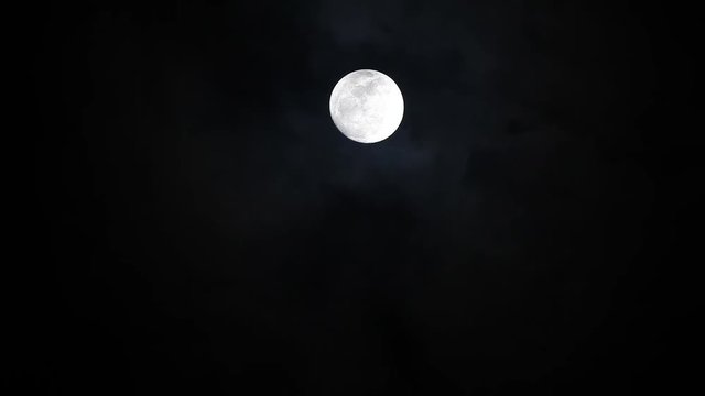Black clouds passing in front of the moon in the night sky. Outdoor at nighttime..