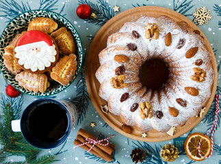 Fruitcake, decor, branches of spruce, plate with a cake and cup of coffee or tea on the green placemat. New year and Christmas decoration concept.  