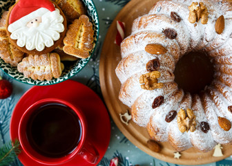 Fruitcake, decor, branches of spruce, plate with a cake and red cup of coffee or tea on the gray wooden table. New year and Christmas decoration concept.  copy space