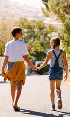 Boy and girl in love walking on street holding hands