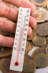 Thermometer in hand beside Turkish Lira coins